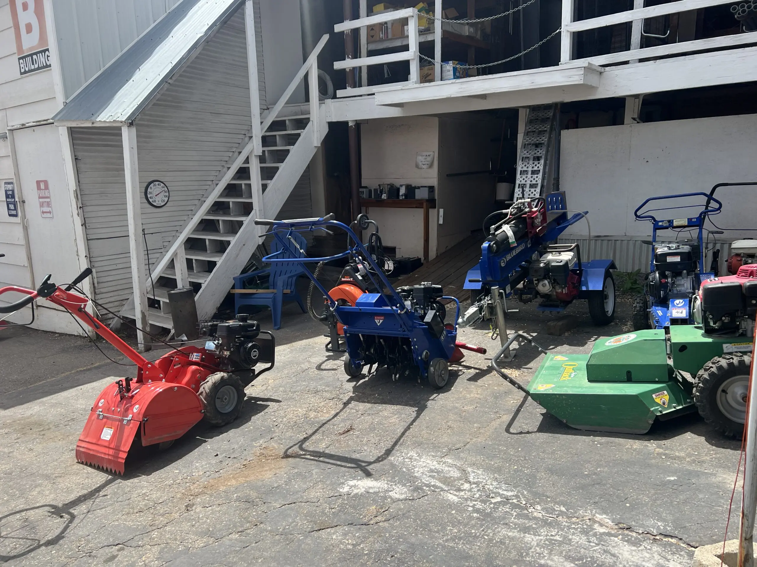 A group of people that are sitting around some lawn mowers.