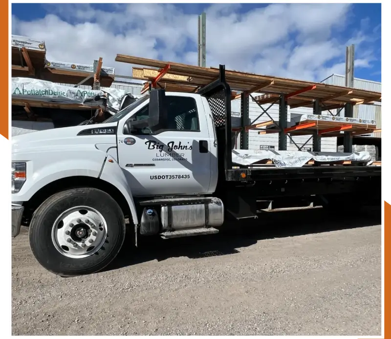 A white flatbed truck with wooden pallets on the back.